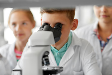 Fototapeta na wymiar education, science and children concept - kids or students with microscope studying biology at school laboratory