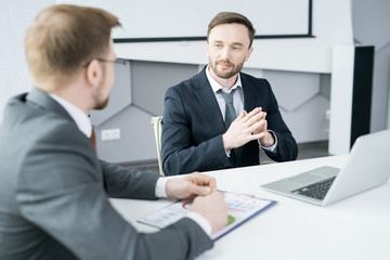 Portrait of handsome businessman listening to partner during meeting in modern office, copy space