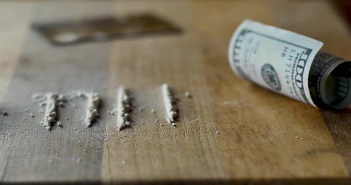 Lines of white powder and a rolled 100 dollar bill representing cocaine or meth