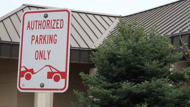 Sign with a tow truck towing a car, the sign reads Authorized Parking Only