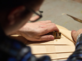 The process of making a classical guitar. Making the right shape of a brace guitar.