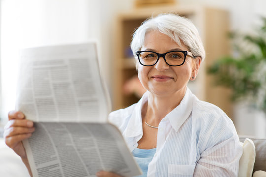 age and people concept - portrait of happy senior woman reading newspaper at home