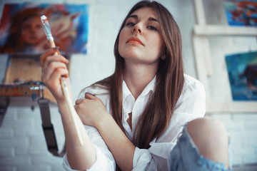 Young artist girl at work in the workshop brush paints canvas inspiration