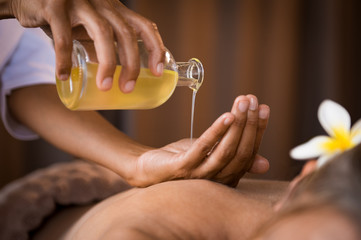 Therapist pouring massage oil at spa - obrazy, fototapety, plakaty