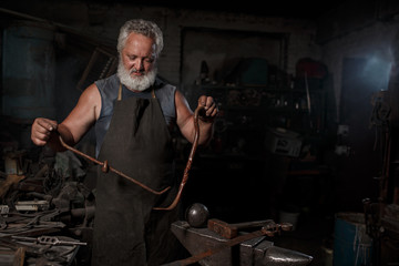 The portrait of blacksmith preparing to work metal on the anvil