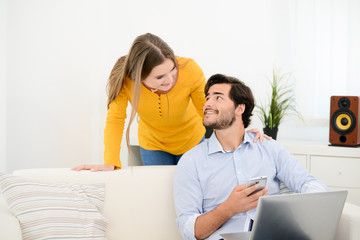 cheerful young couple on sofa at home websurfing and shopping online with laptop computer internet technology