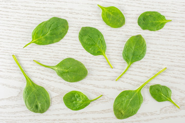 Fresh baby spinach leaves top view on grey wood background.