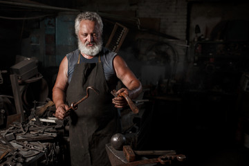 The portrait of blacksmith preparing to work metal on the anvil