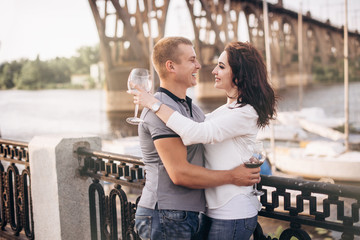 Happy people tasting wine outdoor near river with yachts