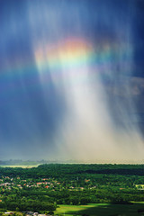 Beautiful rainbow with rainy clouds, colorful summer view