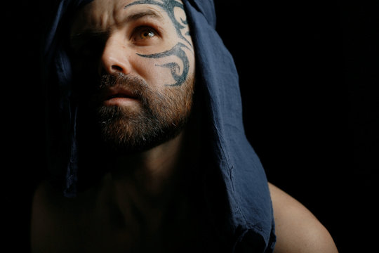 tattoo on the face,  man with a tattoo,  brutal bearded guy, studio portrait of a man