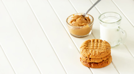 Delicious homemade peanut butter cookies with mug of milk. White wooden background. Healthy snack or tasty breakfast concept. Banner size.