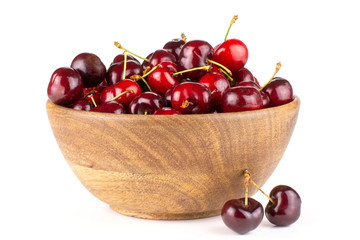 Sweet bright red cherry in a wooden bowl and two is near it isolated on white...........................................................................