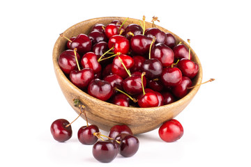 Sweet bright red cherry in a wooden bowl and near it isolated on white...........................................................................