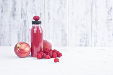 Fresh raspberries, peaches and juice in a plastic bottle. Detox. White background. Copy space.