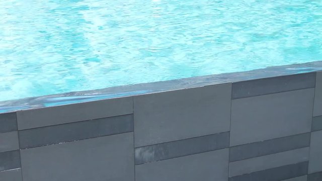 Swimming pool wall with aqua blue waves splashing over.  Pool planning and design for lifestyle and fitness.