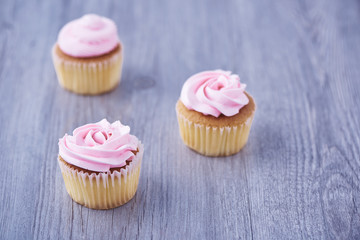 Three delicious cupcakes on wooden background