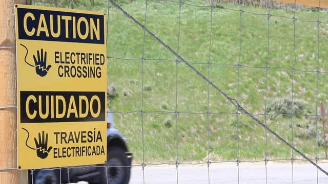 Electric fence sign in Spanish and English.