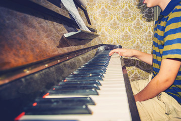 The boy studies chords on notes, sitting at the piano.
