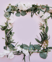Naklejka premium Beautiful fresh floral frame out of eucalyptus leaves and branches and blossoming white lathyrus flowers on the tender pastel pink background