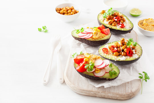 avocado boats stuffed with hummus, tomatoes, radish, roasted chickpea
