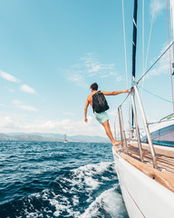 Young man standing on sailboat with a backpack