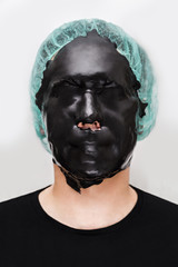 Male patient with skin alginate seaweed black mask on face on white background.