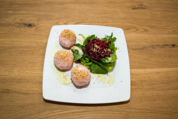 Salad with Beet and Sushi Balls on white Plate on wooden Table.