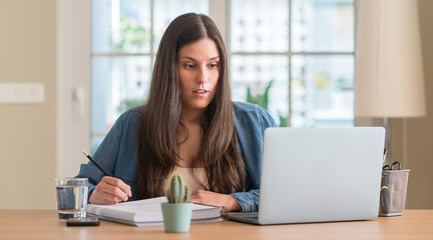 Young student woman studying at home scared in shock with a surprise face, afraid and excited with...