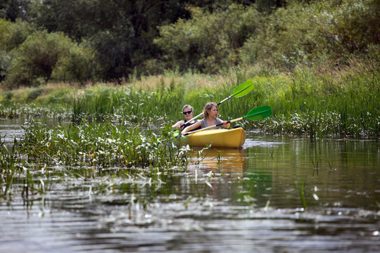 Two happy girls enjoying kayak on the river