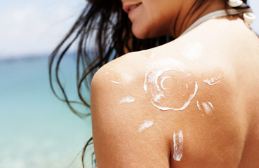 Woman on the beach, swimsuit and suncream lotion sun shape