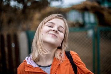 red-haired girl in an orange jacket on the nature. Traveler in the summer in autumn.