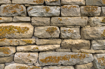 Close-up textured background is an irregular natural stone wall made of different stones without a cement-type bonding mixture. Medieval background