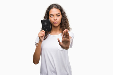 Young hispanic woman holding passport of Australia with open hand doing stop sign with serious and confident expression, defense gesture