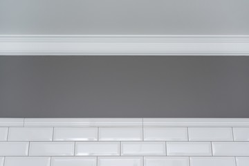 Gray painted wall, white ceiling molding and ceramic decorative tiles small white glossy brick....