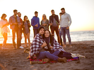 Couple enjoying with friends at sunset on the beach