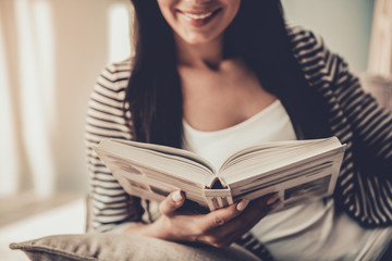 Close up. Young Smiling Woman Reading Book at Home