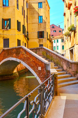Old small arch bridge over canal in Venice