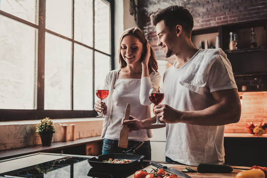 Young Couple Cooking Dinner And Drink Red Wine.