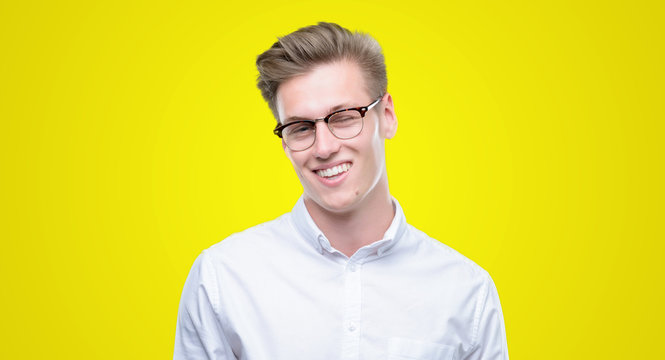 Young handsome blond man winking looking at the camera with sexy expression, cheerful and happy face.