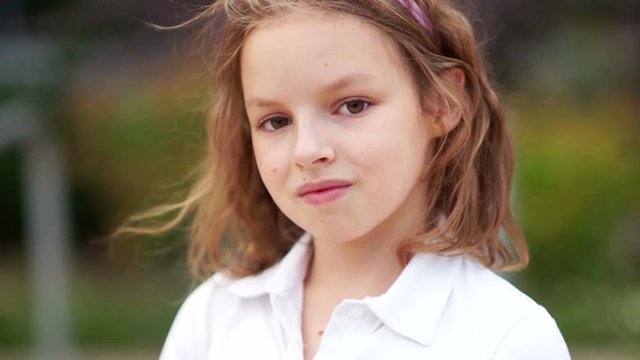 The curly girl looks into the camera with a half-smile, coquettishly and confidently. Young model, natural beauty