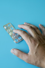 The hand reaches for the pill. vertical photo