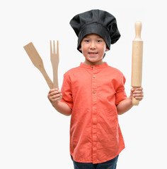 Fototapeta premium Dark haired little child wearing chef uniform with a happy face standing and smiling with a confident smile showing teeth