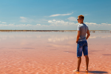Young man is standing in a pink salt lake