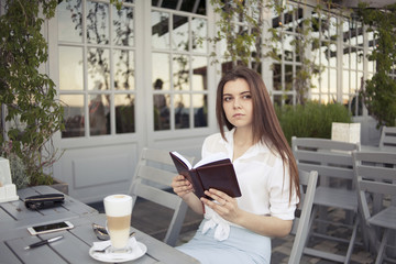 girl in a summer cafe with a book