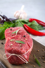 Raw beef steak with ingredients for cooking on cutting board .