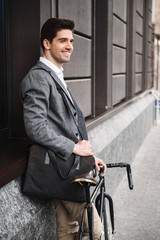 Smiling young businessman leaning on a wall