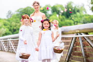 Wedding couple bride and groom with flower children or bridesmaid in white dress and flower baskets