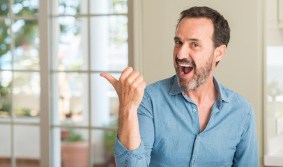 Handsome middle age man pointing with hand and finger up with happy face smiling