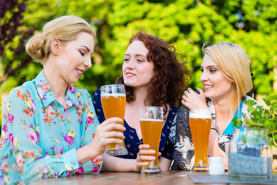Happy friends toasting with beer in garden pub